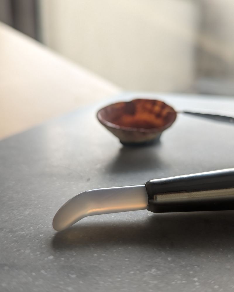 Une coquille garnie de pigment et un brunissoir posés sur la table de l’atelier