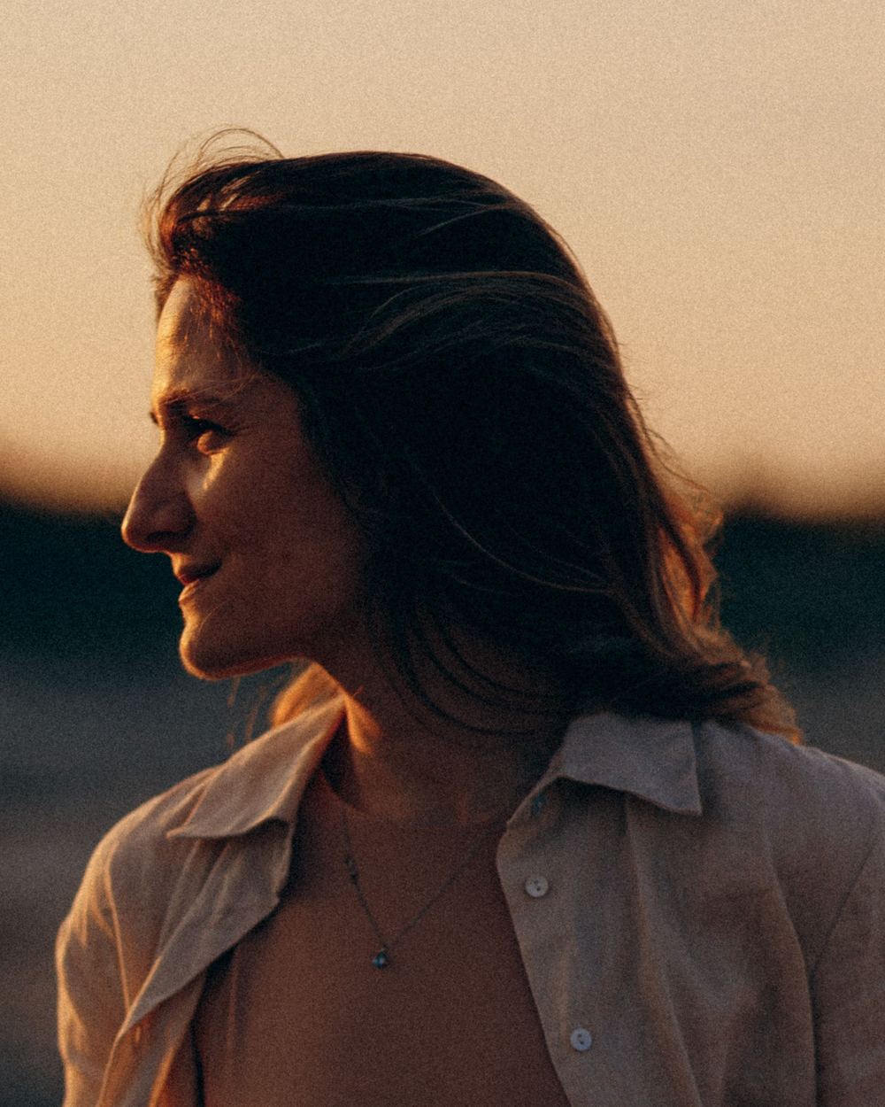 Une femme de profil, souriante, dans la lumière dorée d’un soir d’été
